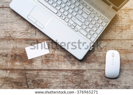 Creative horizontal top view photo of business objects on light colored woodblocks. There are laptop, visit card and optical mouse