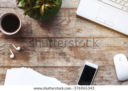 Creative horizontal top view photo of business objects on light colored woodblocks. There are laptop, mobile phone, coffee, plant and optical mouse