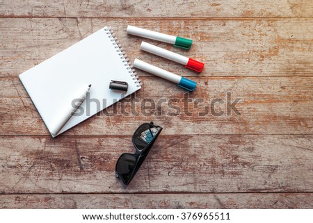 Creative horizontal top view photo of business objects on light colored woodblocks. There are notebook, sunglasses and markers