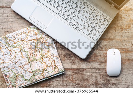 Creative horizontal top view photo of business objects on light colored woodblocks. There are laptop, map and optical mouse