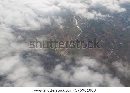 Landscape with green farmland patches and clouds, aerial shot.