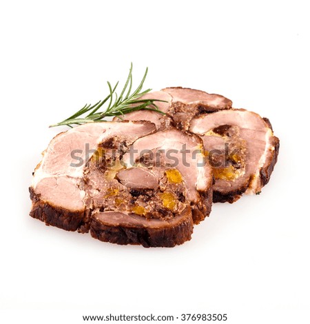Close up of sliced stuffed pork roast with rosemary sprig over isolated white background