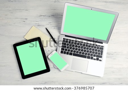 Modern laptop, mobile phone, tablet and notebook on white wooden background