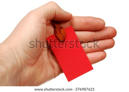 The red tag on brown leather rope in the hand on a white background
