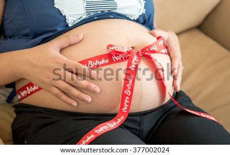 pregnant belly decorated with ribbon as a present