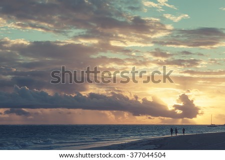 Sunrise over Atlantic ocean. Dominican republic, ordinary tourists walking along Punta Cana beach. Colorful tonal correction photo filter effect