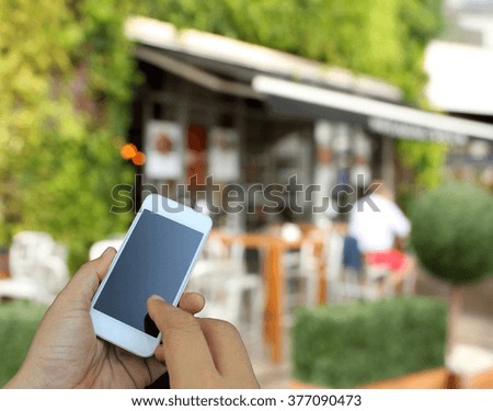 hand holding the smartphone on blur restaurant background,Transactions by smartphone concept