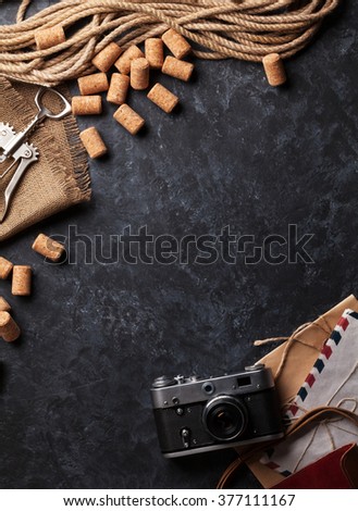 Wine corks, corkscrew, vintage camera and envelopes over dark stone background. Top view with copy space