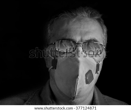 Portrait of a man wearing a mask. Reflection of factory chimneys on his glasses added in photoshop.