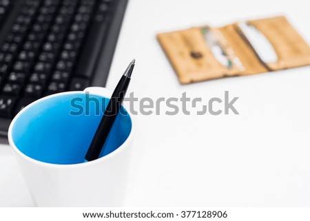 Black pen on white table with blur keyboard and wallet