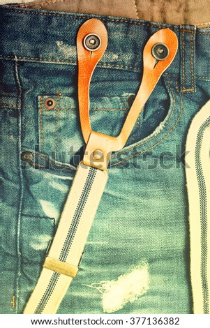 Fashionable youth clothes - jeans with frayed holes and suspenders illuminated yellow light