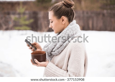 young woman with telephone and hot tea in winter