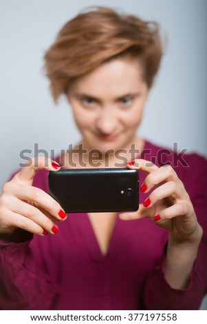 bright woman having fun photographs on the phone with glasses isolated studio