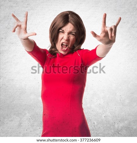Pretty woman making horn gesture over textured background