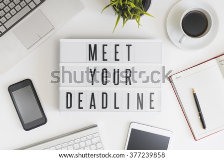 Meet your deadline words on office table with computer, coffee, notepad, smartphone and digital tablet