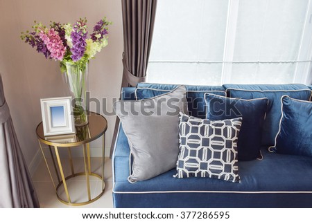 Navy blue modern classic sofa and retro, gray and blue pillows with a lovely orchid vase on side table in living corner