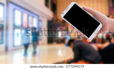 Girl use mobile phone, blur image in the mall as background.