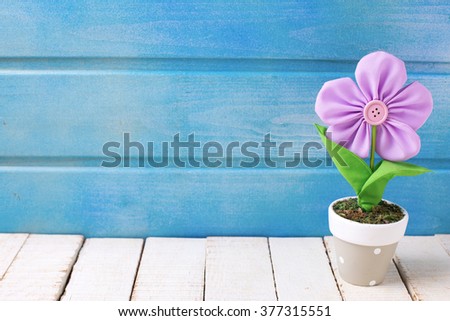 Decorative flower in pot on wooden background. Selective focus. Place for text.