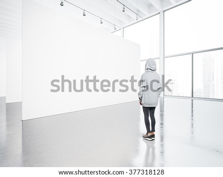 Photo of girl in  contemporary gallery looking at the blank canvas. 