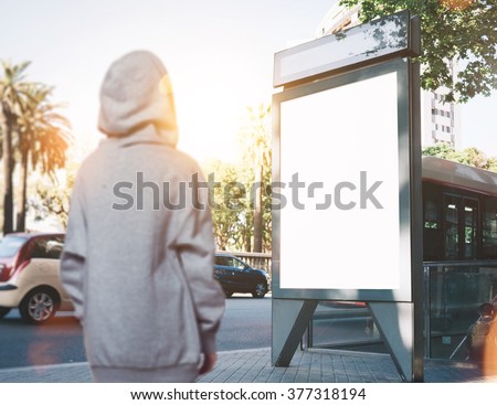 Photo of girl looking at blank lightbox on the bus stop. Horizontal