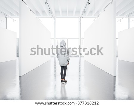 Photo of girl in empty contemporary gallery looking at the blank canvas. 