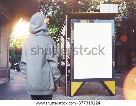Photo of girl looking at empty lightbox on the bus stop. Horizontal