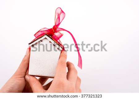 Hand holding a model house with a pink ribbon