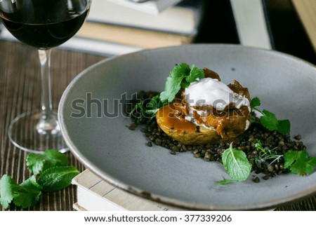 Lamb fillet on legumes with a glass of wine on a wooden table, books on a background