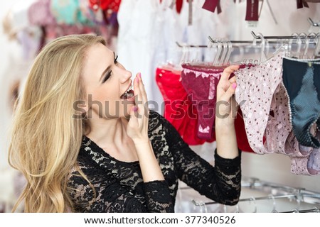 Young woman shopper choosing underwear in shop