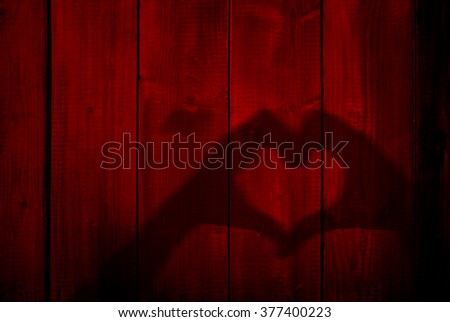 Concept or conceptual Valentine human man and woman hands silhouette as heart or love symbol on old red wood background, metaphor to romantic, romance, relationship, young, couple, wedding or lover