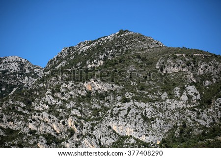 Beautiful heads tops of mountains with cliffs and green foliage trees natural elevation of earth surface on bright blue sky on landscape background, horizontal picture 