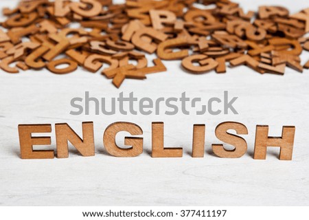 Word English made with wooden letters on a background of other blurred letters