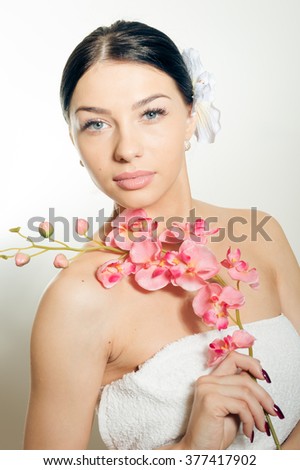 Beautiful woman holding a branch of orchid flowers