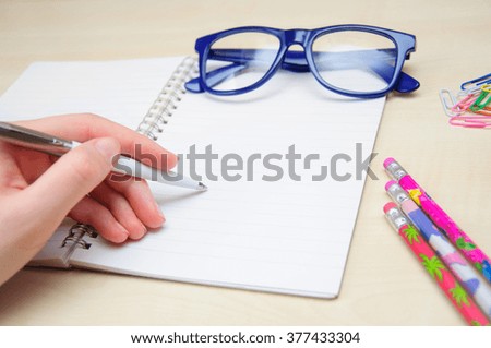 Female hand writing on blank paper notebook