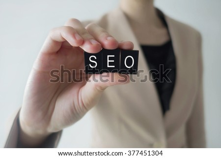 Business women holding SEO letter against a defocussed background with cool image temperature as an Information Technology Concept