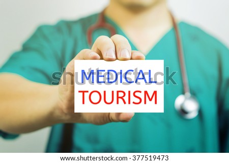 Doctor holding a  business card with capital lettering MEDICAL TOURISM in hand, Medical concept, Selective focus.vintage tone.
