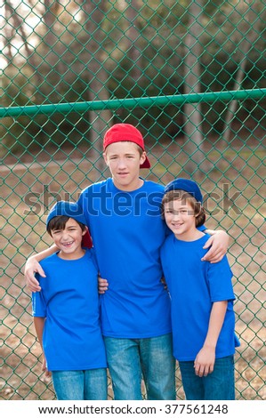 Outdoor portrait of group of three boys that are friends posing after playing backyard baseball.