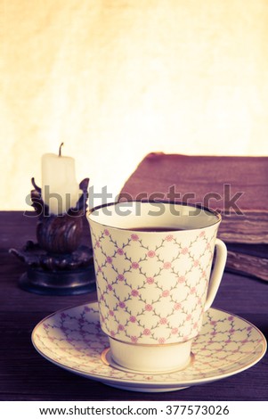 Old books, cup of coffee, candy and ancient candle on the table. Shallow depth of field. Selective focus. Toned.