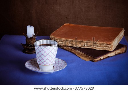 Old books, cup of coffee, candy and ancient candle on the table. Selective focus. Toned.