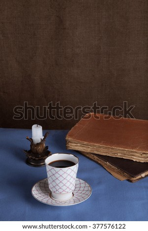 Old books, cup of coffee, candy and ancient candle on the table. Selective focus.