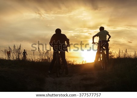 summer landscape silhouette of a boy on a bicycle, with rolling hills on the background of golden sunset 