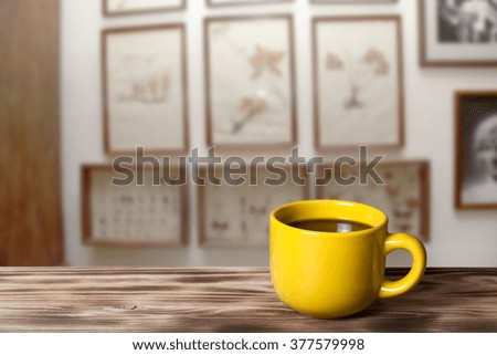 Coffee in a cup on wooden table opposite a defocused the interior of the museum's room for background. Collage. Selective Focus.