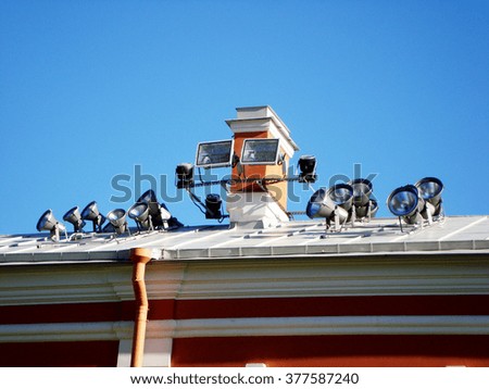 Roof of the house with spotlights on blue sky background
