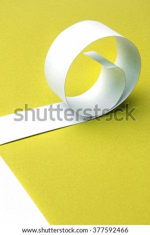 Cutted and rolled white paper with yellow background