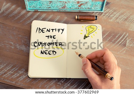 Retro effect and toned image of a woman hand writing a note with a fountain pen on a notebook. Handwritten text IDENTIFY THE CUSTOMER NEED next to yellow lighting bulb as symbol for bright idea. Royalty-Free Stock Photo #377602969