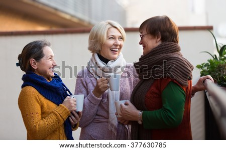 Portrait of cheerful senior female friends drinking coffee at patio. Focus on blonde
