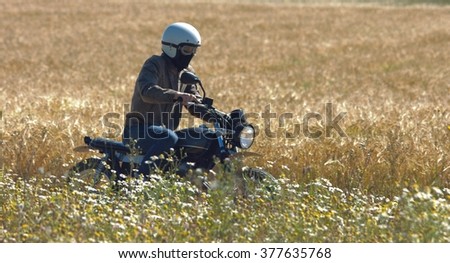 Retro motorcyclist riding in the middle of the field.