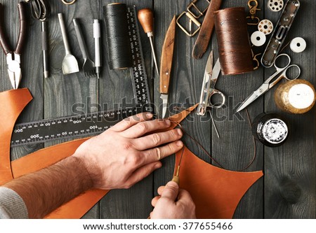 Man working with leather using crafting DIY tools 