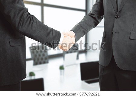 Handshake of two businessmen in office, closeup