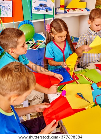 Group kids holding colored paper on lesson in kindergarten .